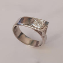Load image into Gallery viewer, A platinum band ring with a central square-cut diamond, reflective metallic surface.