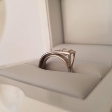 Load image into Gallery viewer, A platinum band ring with a central square-cut diamond in a white box