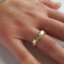 Load image into Gallery viewer, A chunky, textured wedding ring made from recycled 9ct yellow gold worn on models hand.
